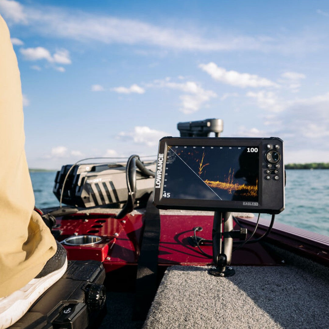 Fishing boat with a fish finder on the deck, person wearing a beige jacket, and clear blue sky.