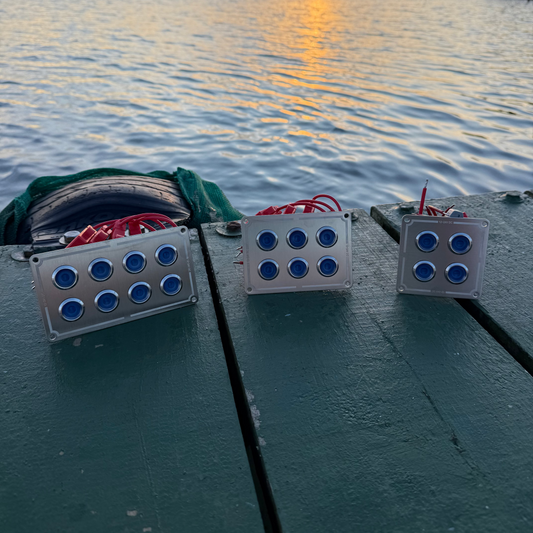 Three electronic devices with blue lights on a dock during sunset.