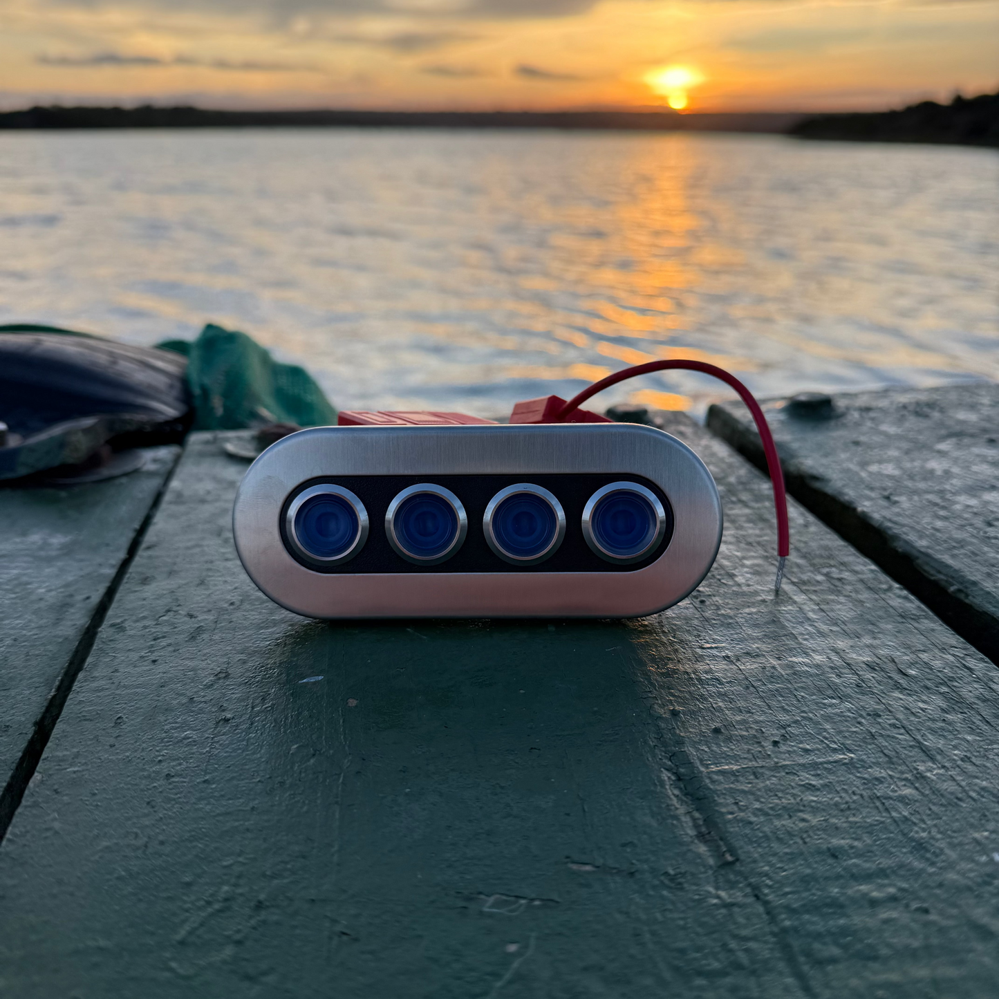 Electronic device with blue lights on a wooden surface during sunset by a lake