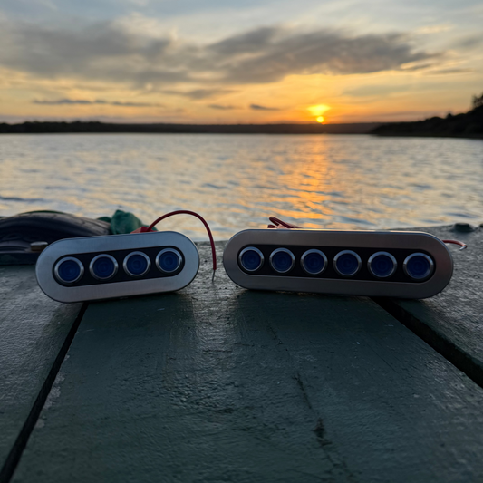 Two electronic devices with blue lights on a dock during sunset.