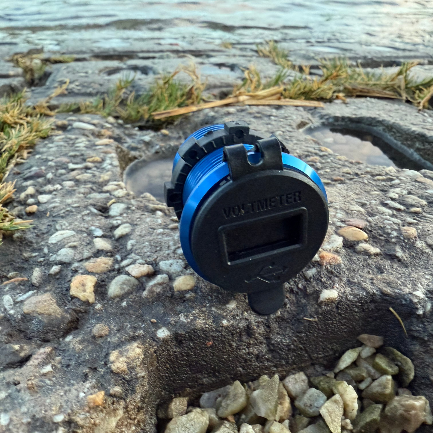 Blue and black device on a stone surface near water