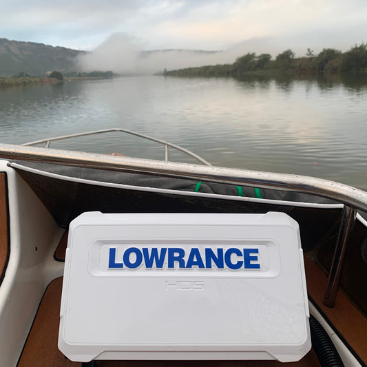 Lowrance device on a boat with a scenic water background