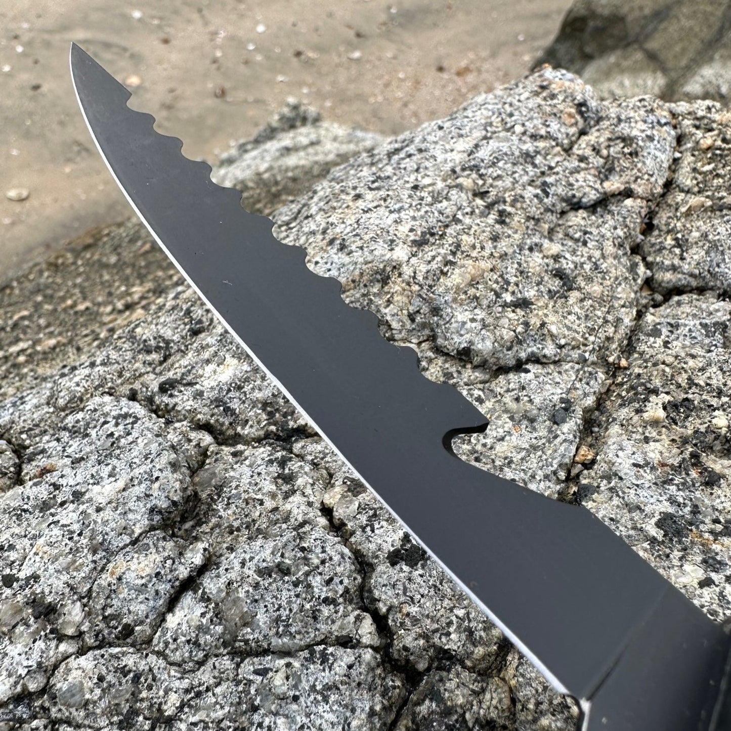 Close-up of a black serrated fillet knife blade designed for efficient fish cleaning, scaling and cutting tasks.