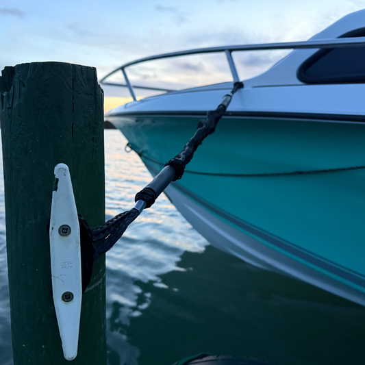 Teal boat tied to a dock with a sunset in the background