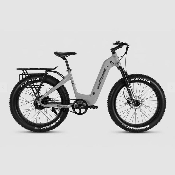 A light gray step-through electric fat tire bike with black components, rear rack, and knobby tires, shown from a side profile on a solid light gray background. Visible brands include Southbound on the frame and Kenda on the tires.