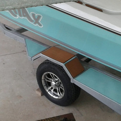 Close-up of a turquoise and white boat trailer with a single wheel, silver chrome rim, and brown wooden deck steps on a concrete floor.