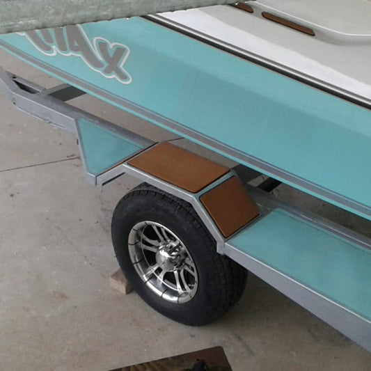 Close-up of a turquoise and white boat trailer with a single wheel, silver chrome rim, and brown wooden deck steps on a concrete floor.