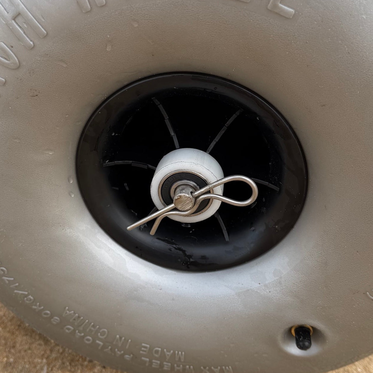 Close-up of the low-pressure balloon wheel hub and quick-release axle pin designed for smooth movement across soft beach sand.