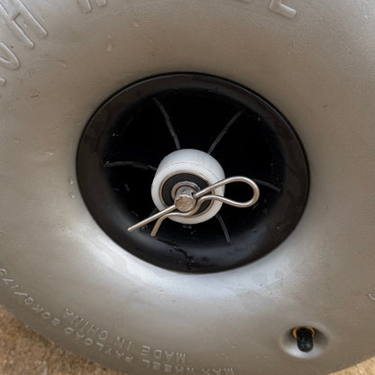 Close-up of the low-pressure balloon wheel hub and quick-release axle pin designed for smooth movement across soft beach sand.