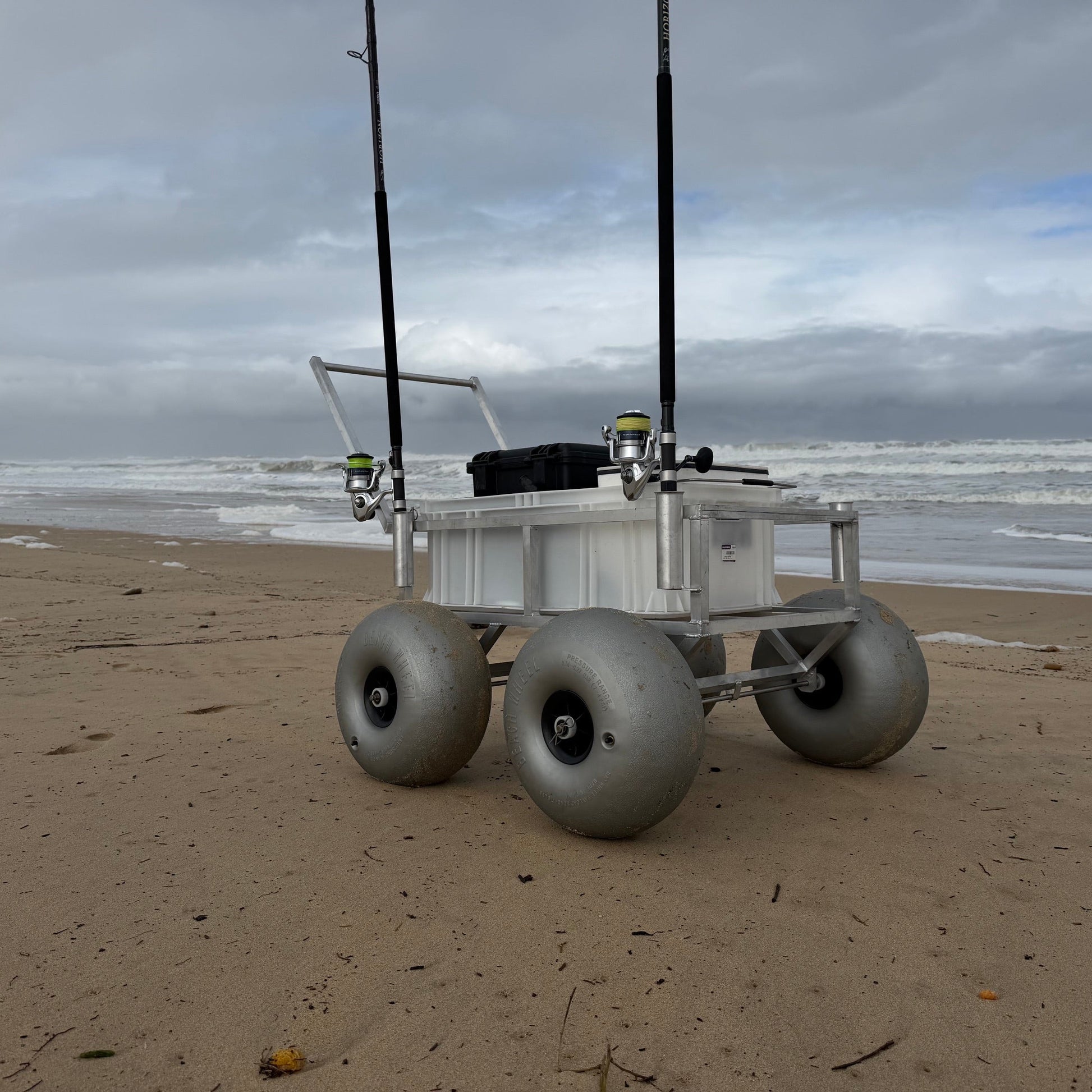 Tidal Hook beach fishing cart featuring oversized balloon wheels, rod holders, and storage crate for effortless transport of surf fishing gear across sandy beaches.