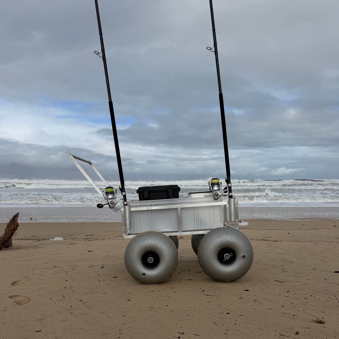 Tidal Hook beach fishing cart with balloon wheels and rod holders positioned on the shoreline, ready for surf fishing adventures.