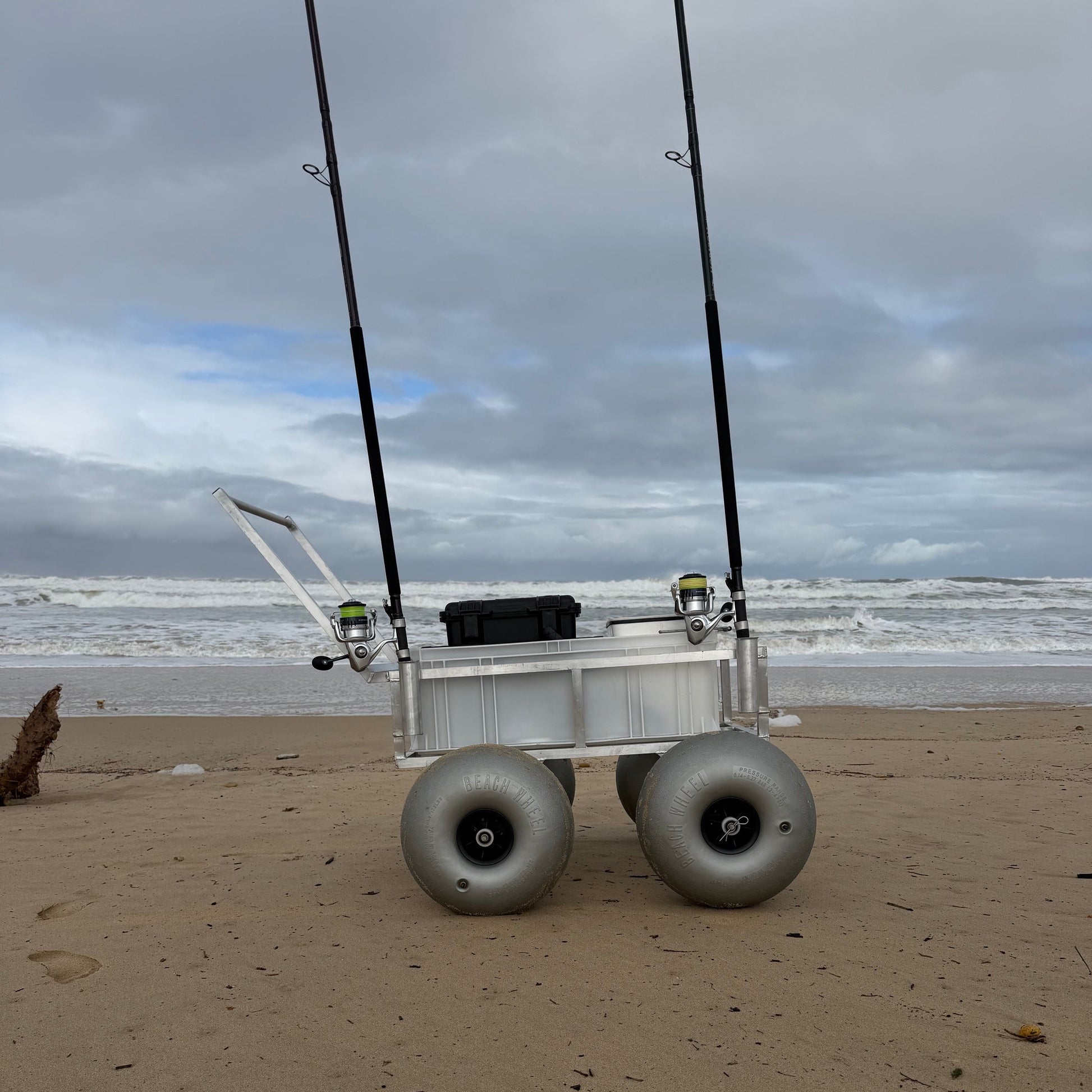Tidal Hook beach fishing cart with balloon wheels and rod holders positioned on the shoreline, ready for surf fishing adventures.