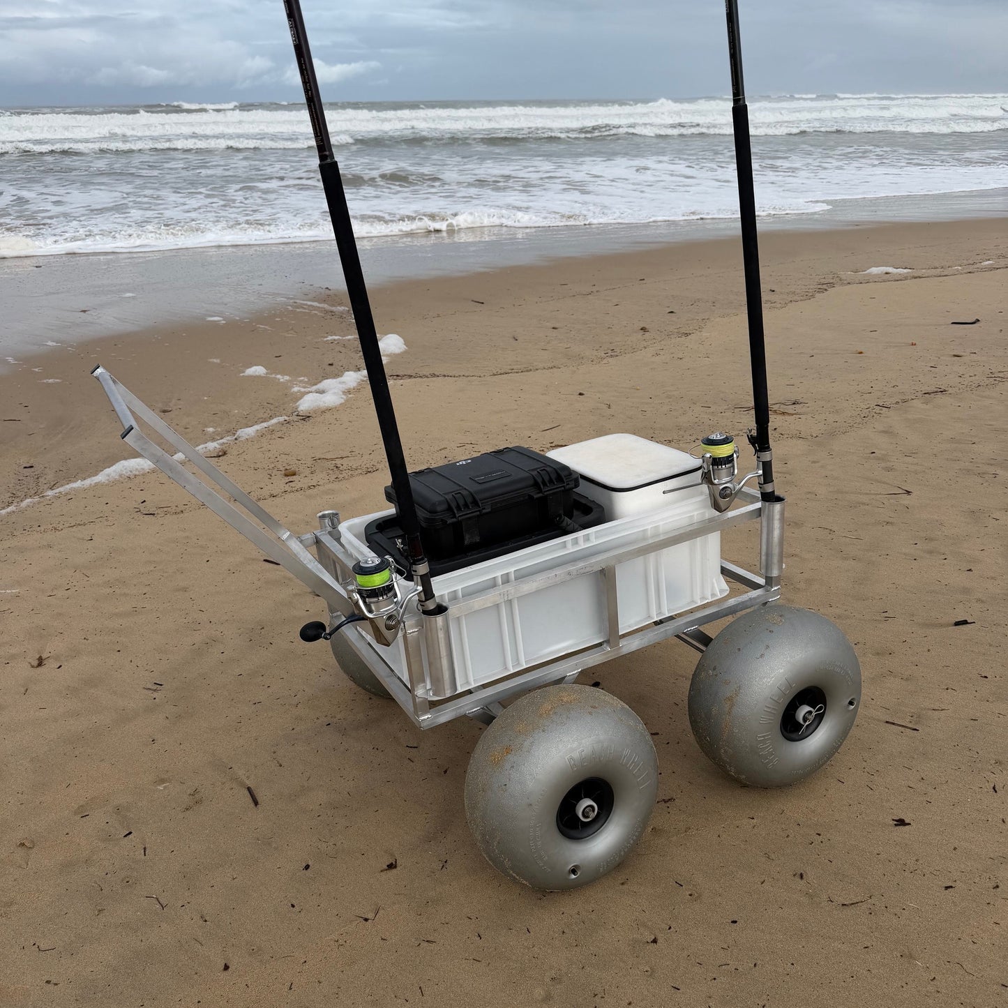 Tidal Hook beach fishing cart with oversized balloon wheels, rod holders, and storage box for transporting fishing gear across soft sand.
