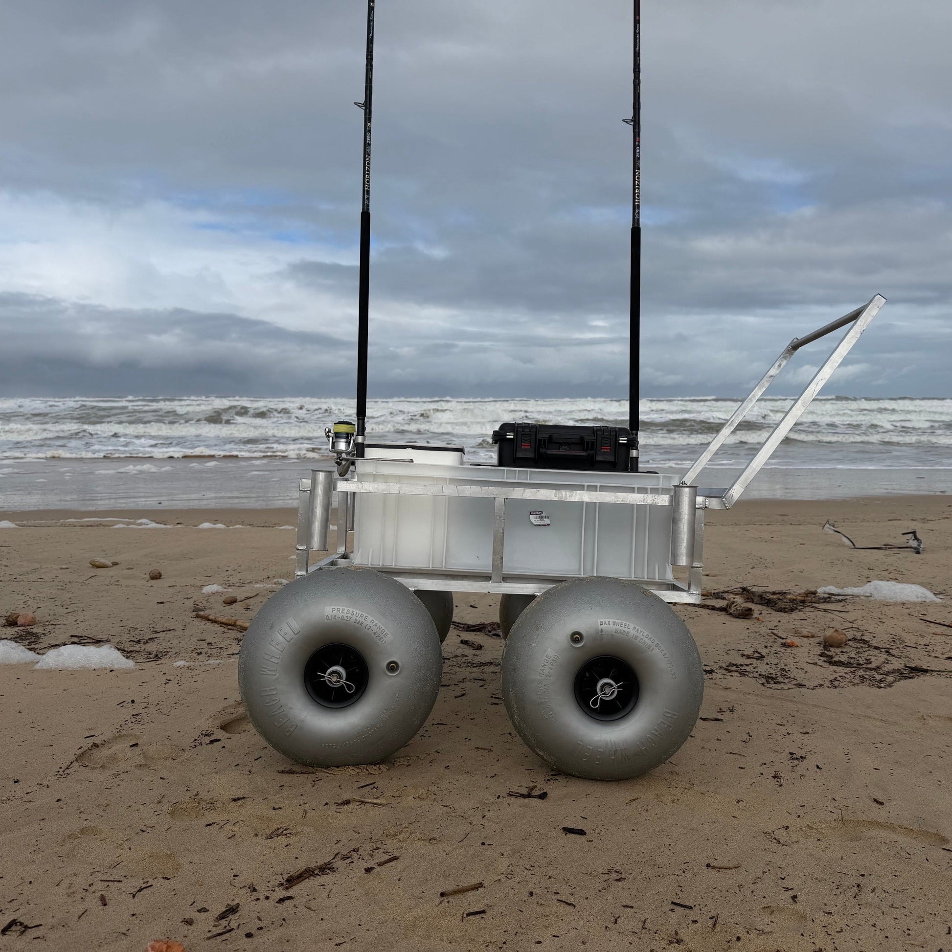 Tidal Hook beach fishing cart with oversized balloon wheels, rod holders, and storage compartment designed for easy transport across soft sand.